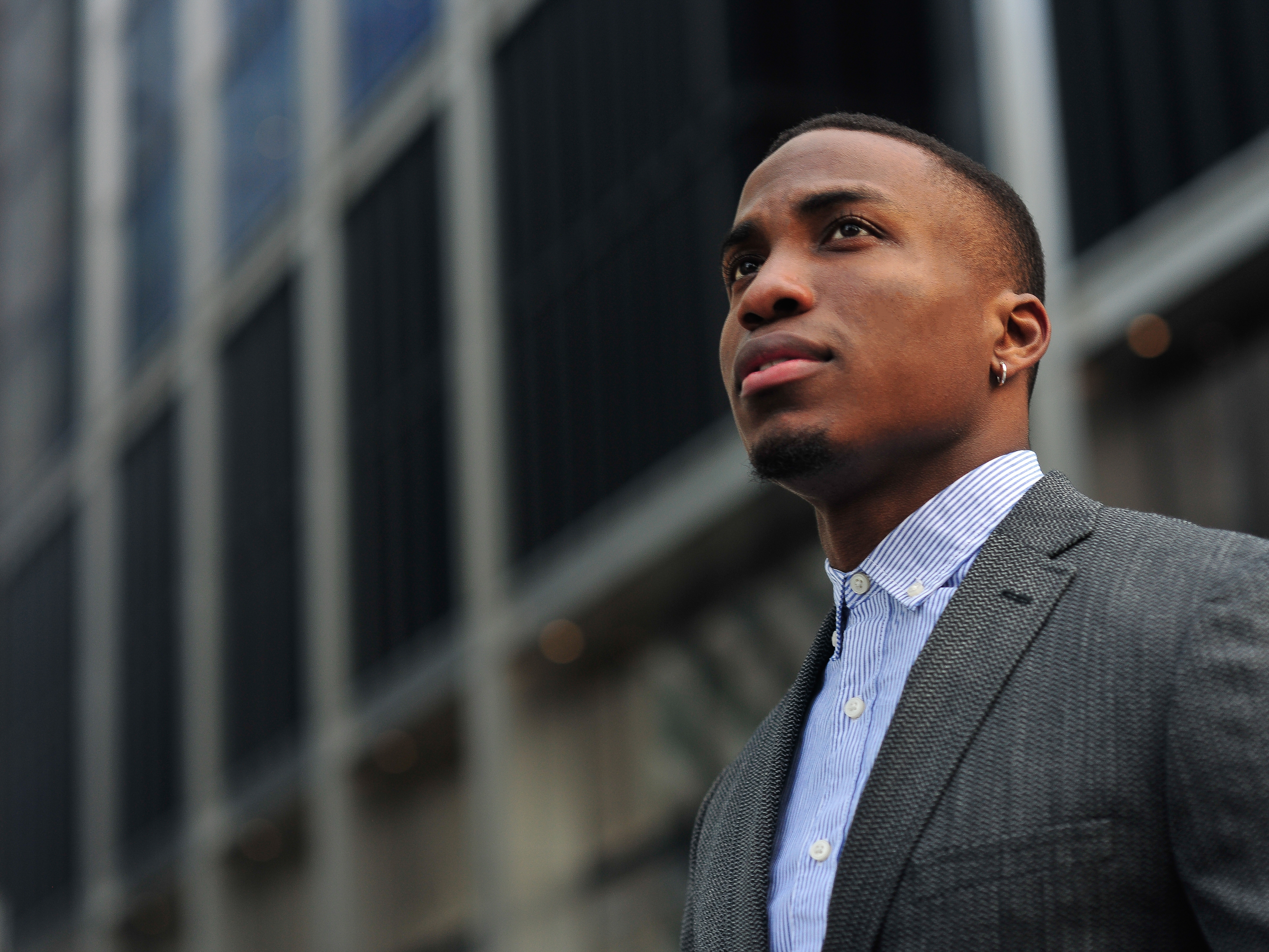 Young Black professional looking upward with confidence in the city