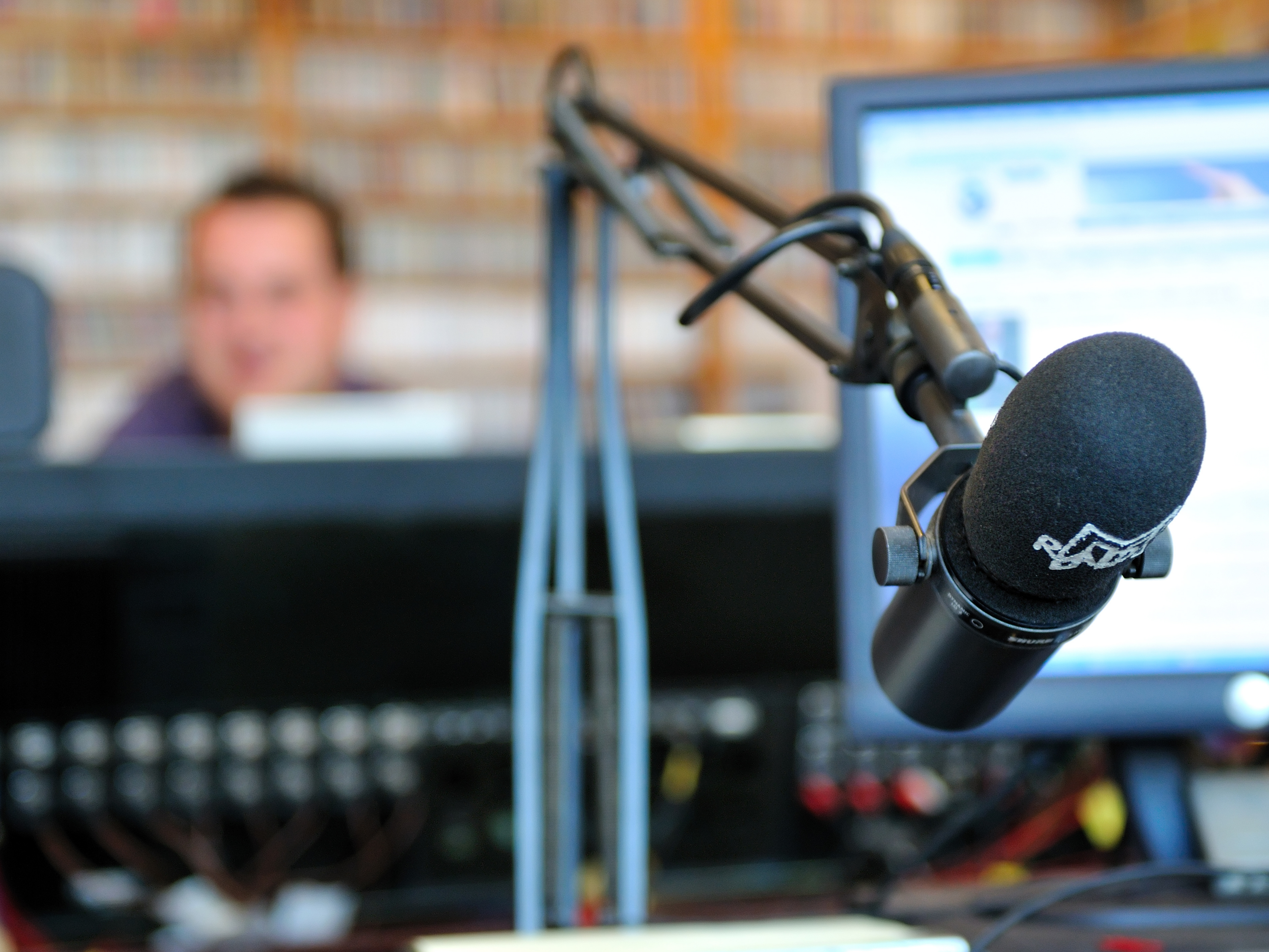Radio host at a studio microphone with mixing equipment