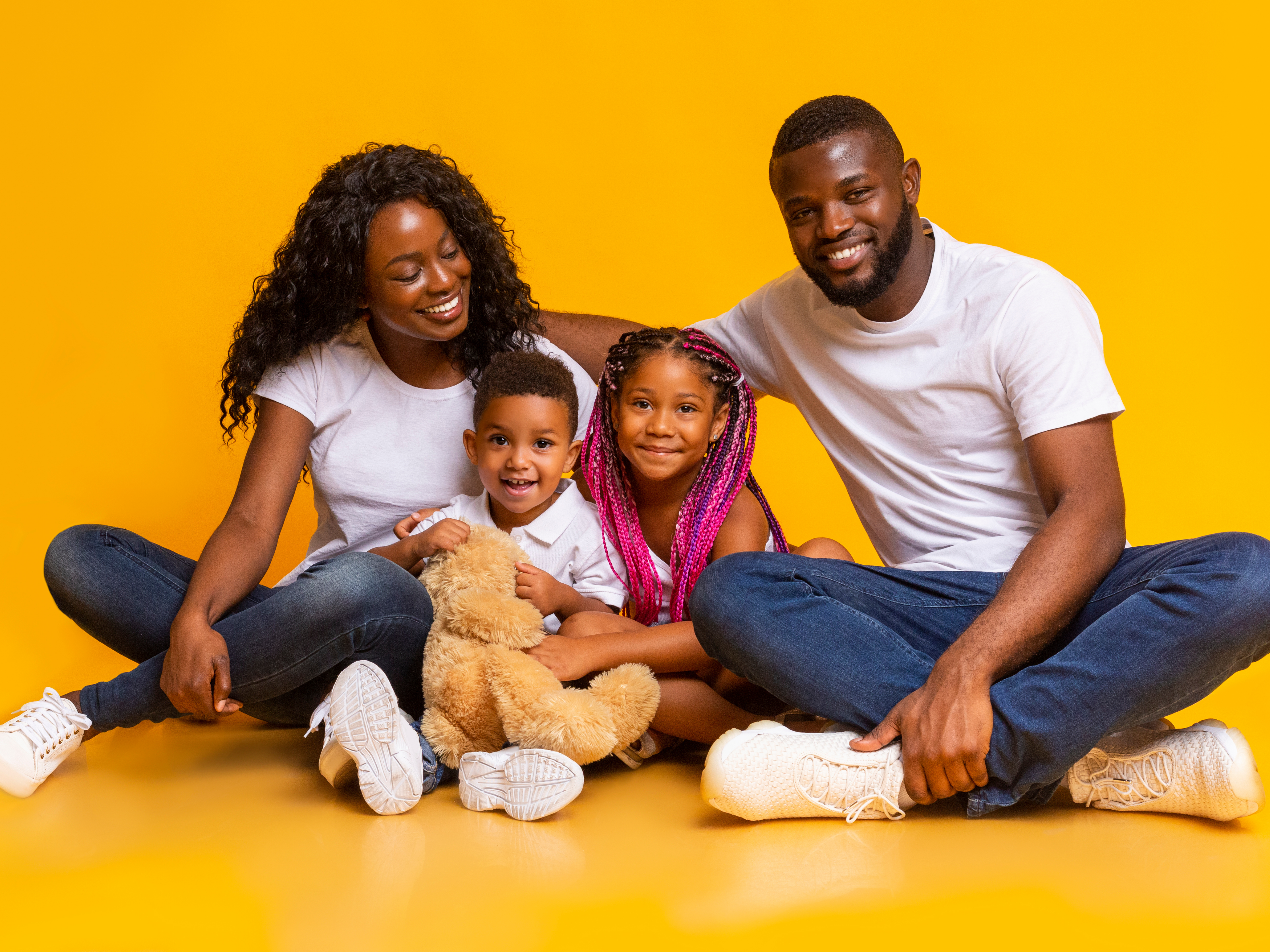 Happy family of four on a bright studio backdrop