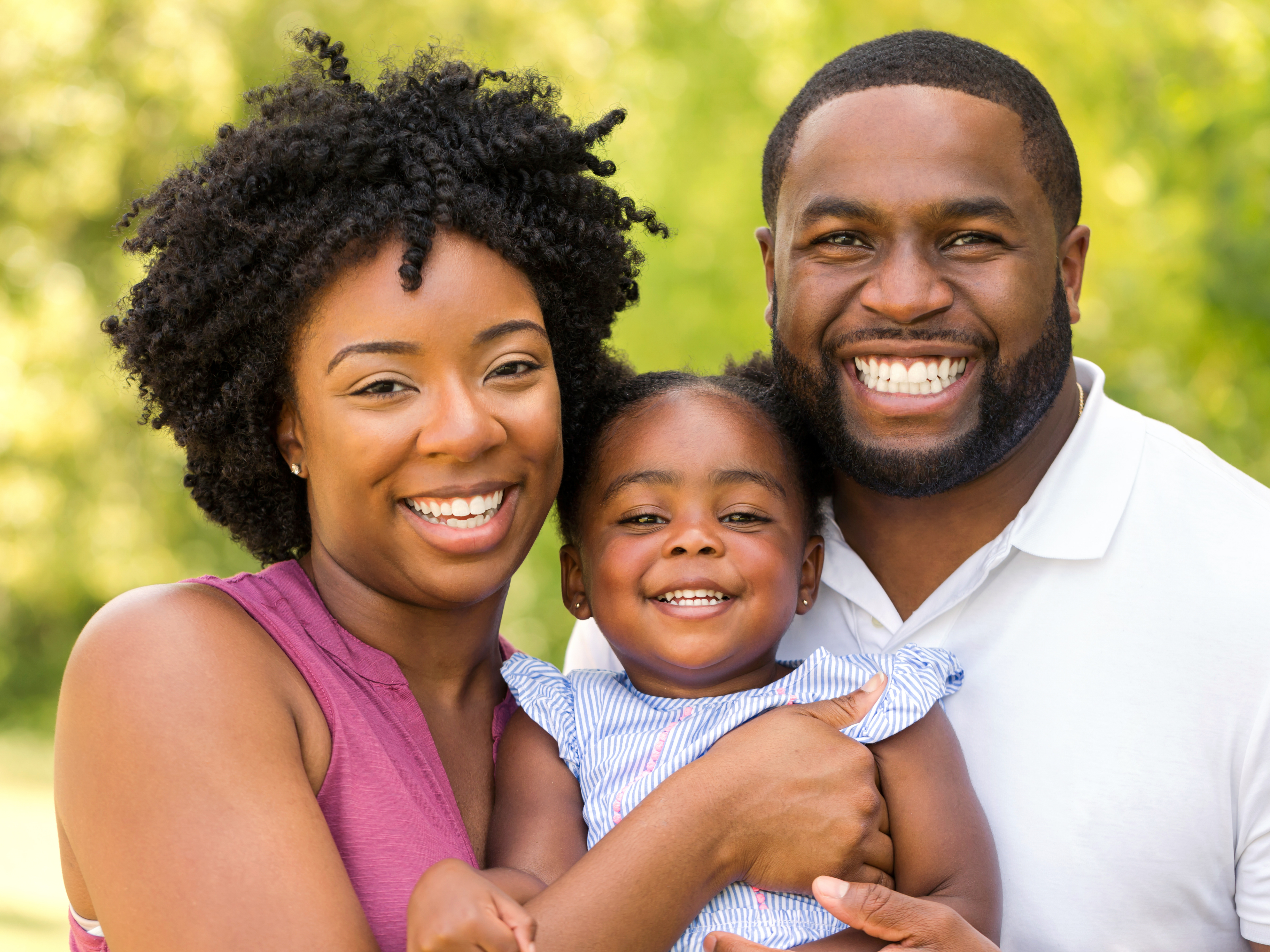 Smiling parents and young daughter outdoors