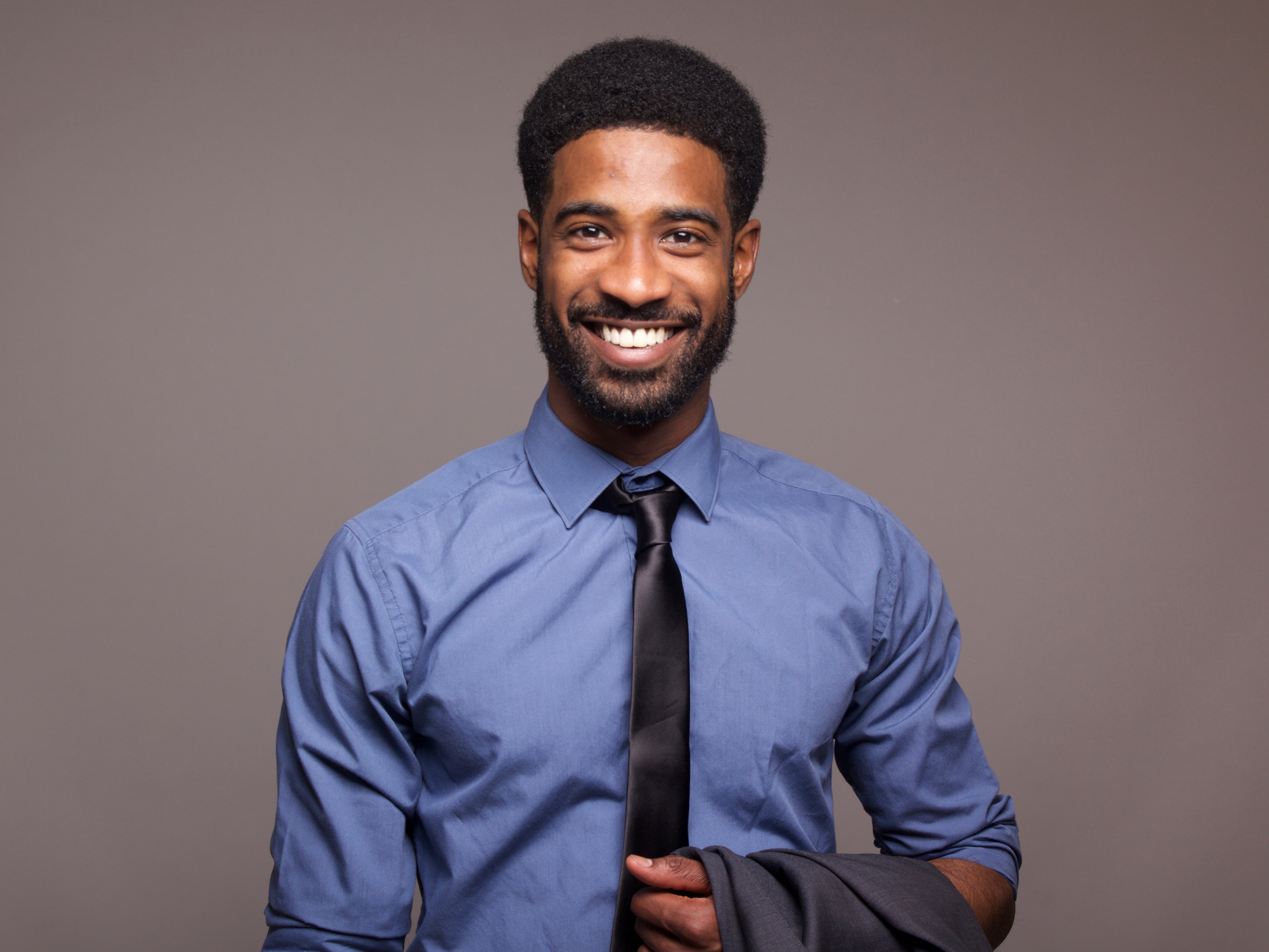 Smiling Black professional in business attire holding a suit jacket